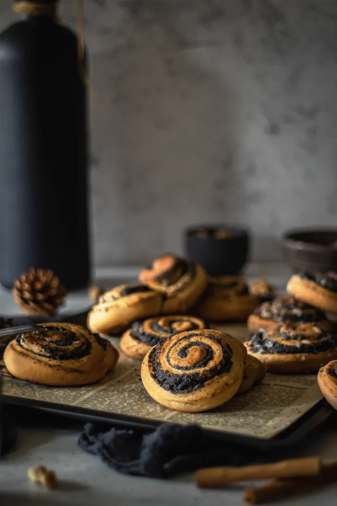 Goldbraune, frisch gebackene Mohnschnecken auf altem Zeitungspapier, fotografiert von David für Seiner Kochbackwelt – perfekt inszeniert für den Genussmoment.