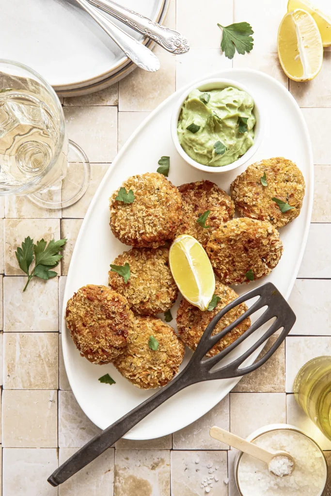 Gemüse-Bratlinge mit Avocado-Tahini-Dip, inspiriert von der Levante-Küche, serviert auf einem Teller mit frischen Kräutern und orientalischen Aromen.