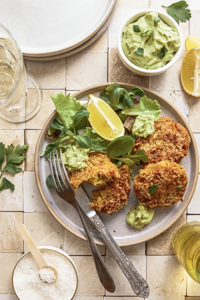 Gemüse-Bratlinge mit Avocado-Tahini-Dip, inspiriert von der Levante-Küche, serviert auf einem Teller mit frischen Kräutern und orientalischen Aromen.