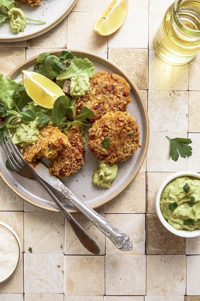 Gemüse-Bratlinge mit Avocado-Tahini-Dip, inspiriert von der Levante-Küche, serviert auf einem Teller mit frischen Kräutern und orientalischen Aromen.