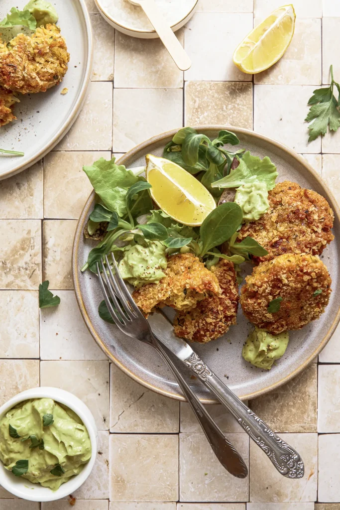 Gemüse-Bratlinge mit Avocado-Tahini-Dip, inspiriert von der Levante-Küche, serviert auf einem Teller mit frischen Kräutern und orientalischen Aromen.