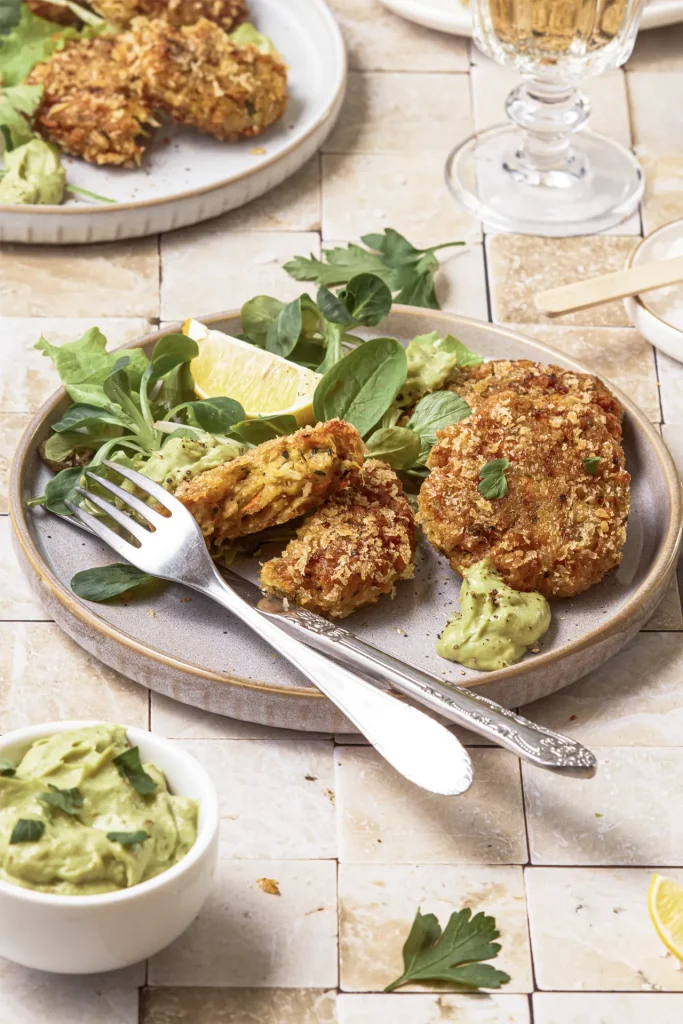 Gemüse-Bratlinge mit Avocado-Tahini-Dip, inspiriert von der Levante-Küche, serviert auf einem Teller mit frischen Kräutern und orientalischen Aromen.