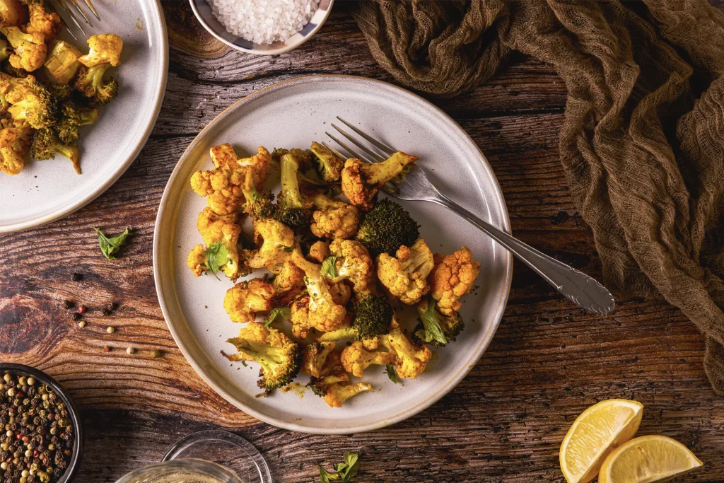 Knuspriges Karfiol-Brokkoli-Popcorn, veganer Snack, gesund und lecker, perfekt für den Veganuary, auf einem Backblech angerichtet, goldbraun gebacken.