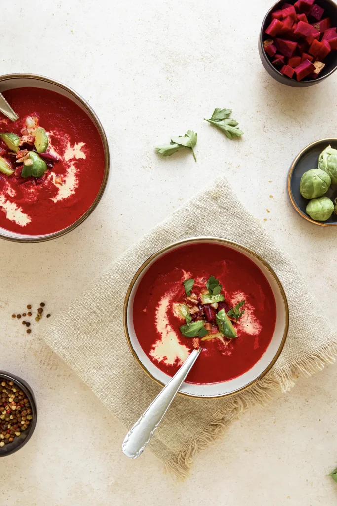 Leuchtend rote Rote-Bete-Suppe in einer Schale, garniert mit frischen Kräutern und einem Klecks Joghurt – ein farbenfroher und gesunder Wintergenuss.