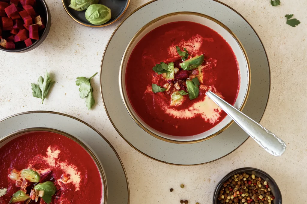 Leuchtend rote Rote-Bete-Suppe in einer Schale, garniert mit frischen Kräutern und einem Klecks Joghurt – ein farbenfroher und gesunder Wintergenuss.