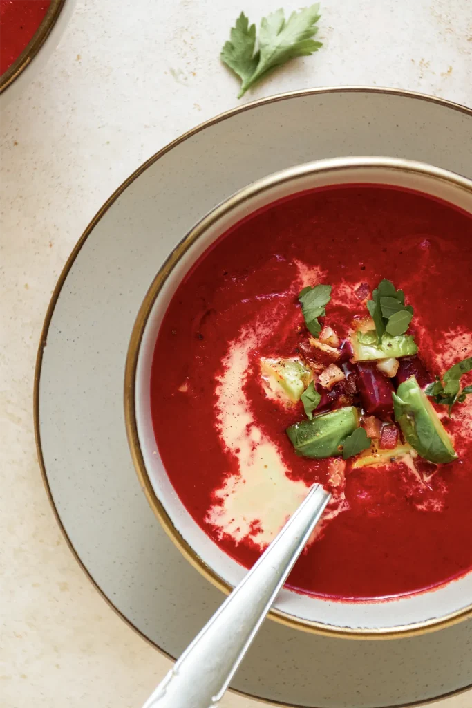 Leuchtend rote Rote-Bete-Suppe in einer Schale, garniert mit frischen Kräutern und einem Klecks Joghurt – ein farbenfroher und gesunder Wintergenuss.