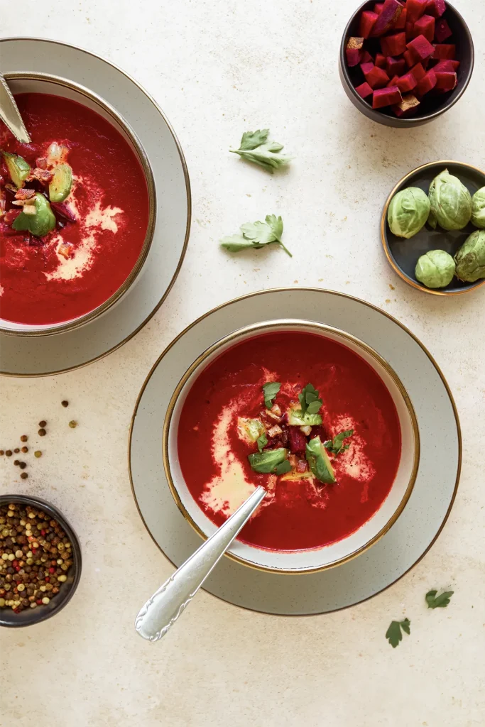 Leuchtend rote Rote-Bete-Suppe in einer Schale, garniert mit frischen Kräutern und einem Klecks Joghurt – ein farbenfroher und gesunder Wintergenuss.