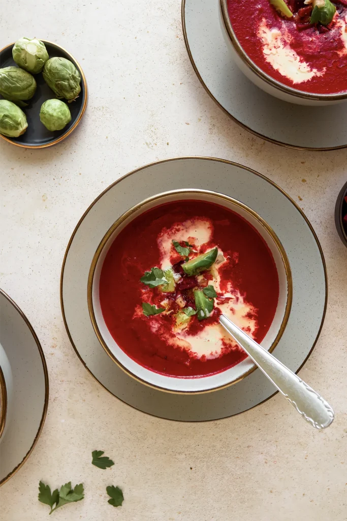 Leuchtend rote Rote-Bete-Suppe in einer Schale, garniert mit frischen Kräutern und einem Klecks Joghurt – ein farbenfroher und gesunder Wintergenuss.