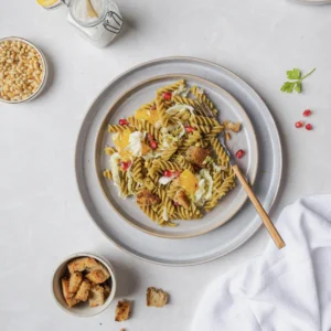 Winterlicher Erbsen-Fusilli-Salat mit Granatapfelkernen, Walnüssen, Orangenfilets, Pinienkernen und knusprigen Brotwürfeln, fotografiert von Kochbackwelt David Steiner.