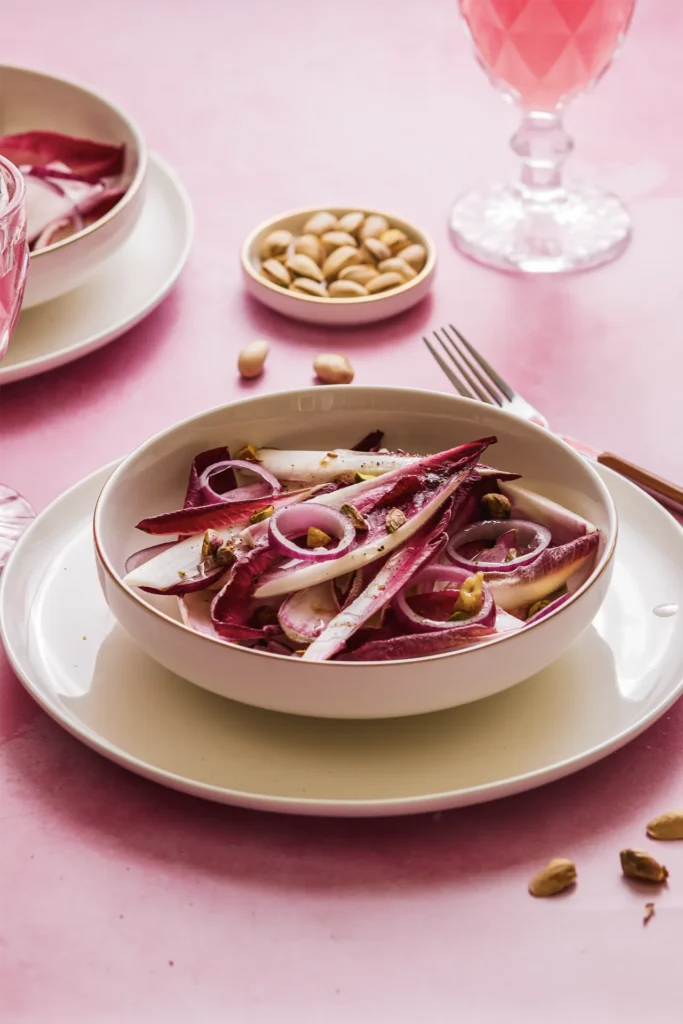 Knackiger Chicorée-Salat mit roten Zwiebeln, Walnüssen und Pistazien – ein leichtes, nussiges Gericht mit modernem Twist.