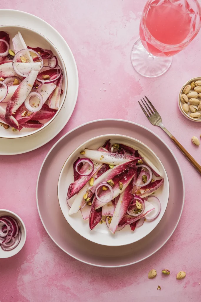 Knackiger Chicorée-Salat mit roten Zwiebeln, Walnüssen und Pistazien – ein leichtes, nussiges Gericht mit modernem Twist.