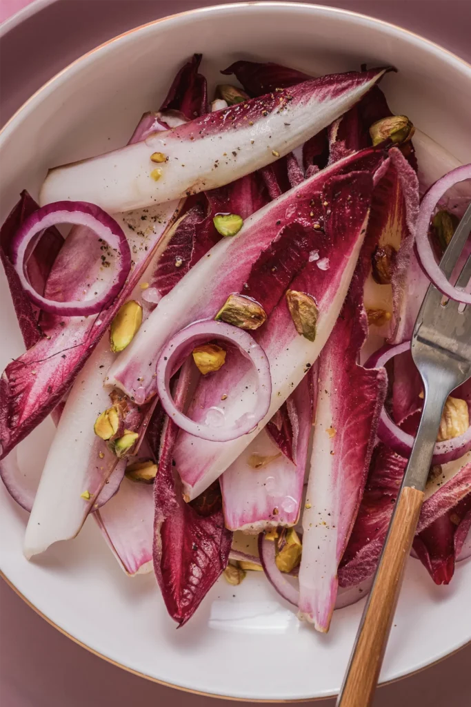 Knackiger Chicorée-Salat mit roten Zwiebeln, Walnüssen und Pistazien – ein leichtes, nussiges Gericht mit modernem Twist.