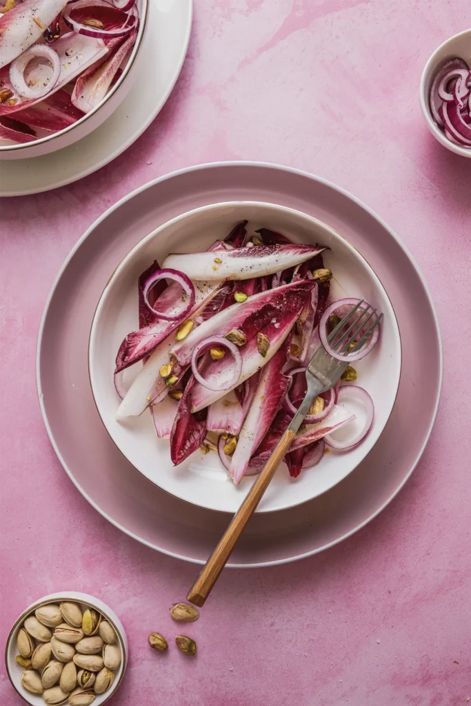 Knackiger Chicorée-Salat mit roten Zwiebeln, Walnüssen und Pistazien – ein leichtes, nussiges Gericht mit modernem Twist.