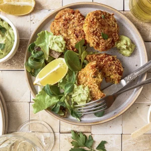 Gemüse-Bratlinge mit Avocado-Tahini-Dip, inspiriert von der Levante-Küche, serviert auf einem Teller mit frischen Kräutern und orientalischen Aromen.