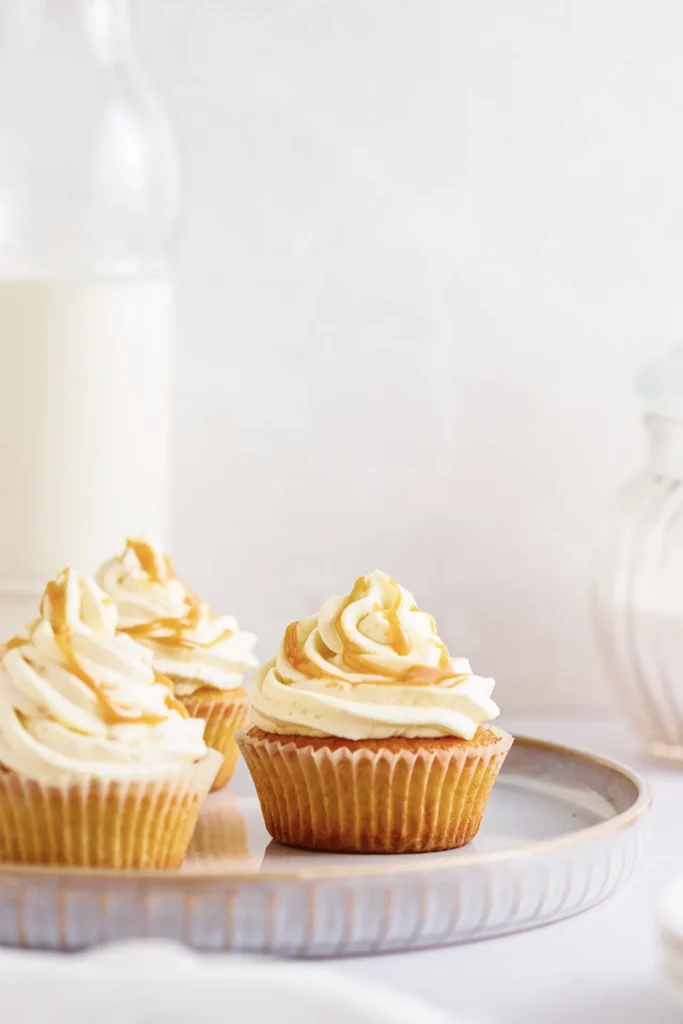 Karamell-Cupcakes mit cremigem Frosting, goldener Karamellsauce und dekorativen Topping