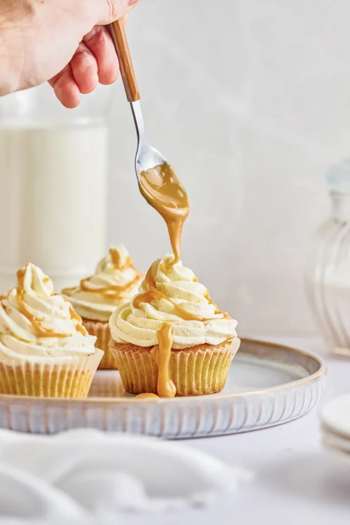 Karamell-Cupcakes mit cremigem Frosting, goldener Karamellsauce und dekorativen Topping