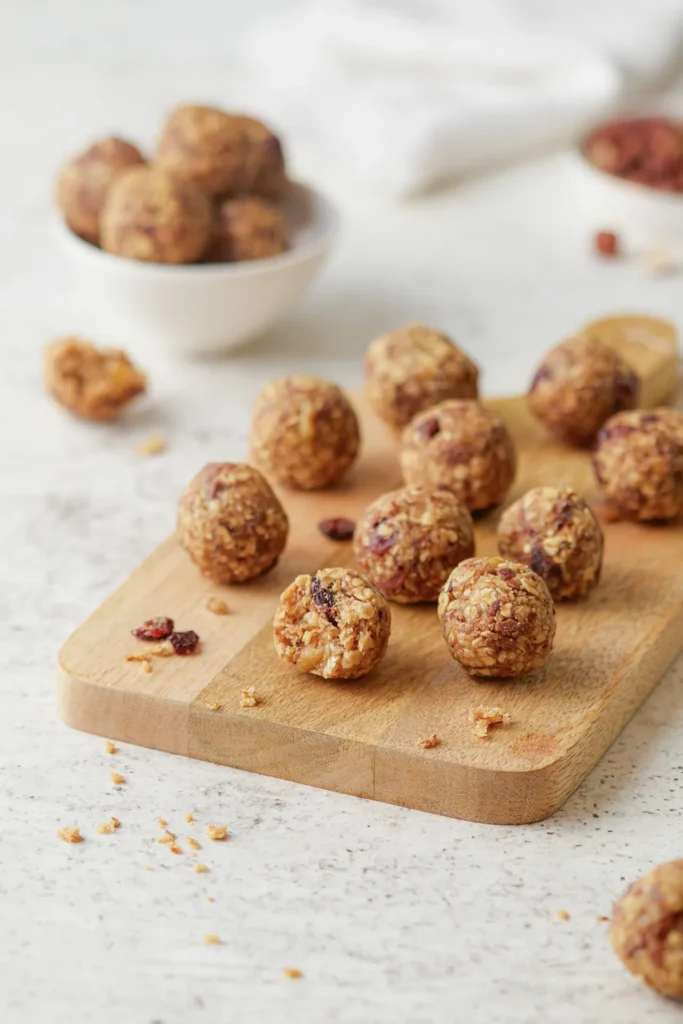 Gesunde Müsli-Bites mit Haferflocken, Leinsamen, Nüssen, Erdnussbutter und Honig auf einem rustikalen Holzbrett, idealer Snack für zwischendurch.