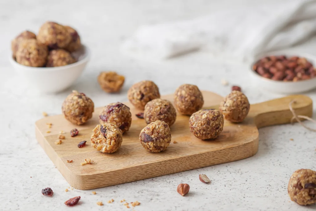 Gesunde Müsli-Bites mit Haferflocken, Leinsamen, Nüssen, Erdnussbutter und Honig auf einem rustikalen Holzbrett, idealer Snack für zwischendurch.