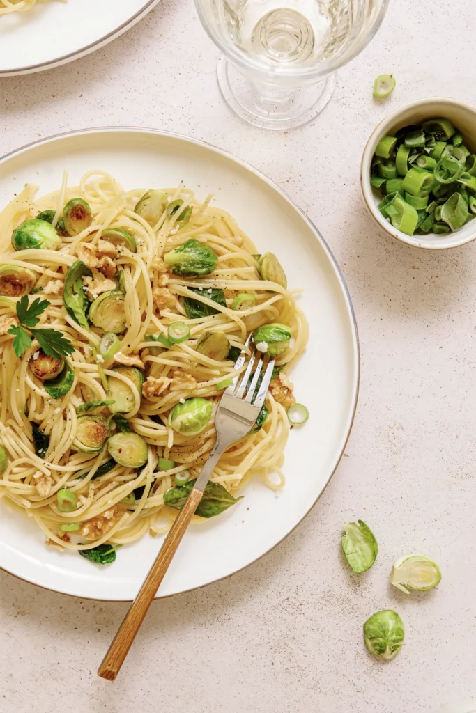 „Spaghetti mit Rosenkohl, Walnüssen und Spinat – winterliches Pastagericht mit knackigem Gemüse, nussiger Note und frischem Spinat auf rustikalem Teller.“