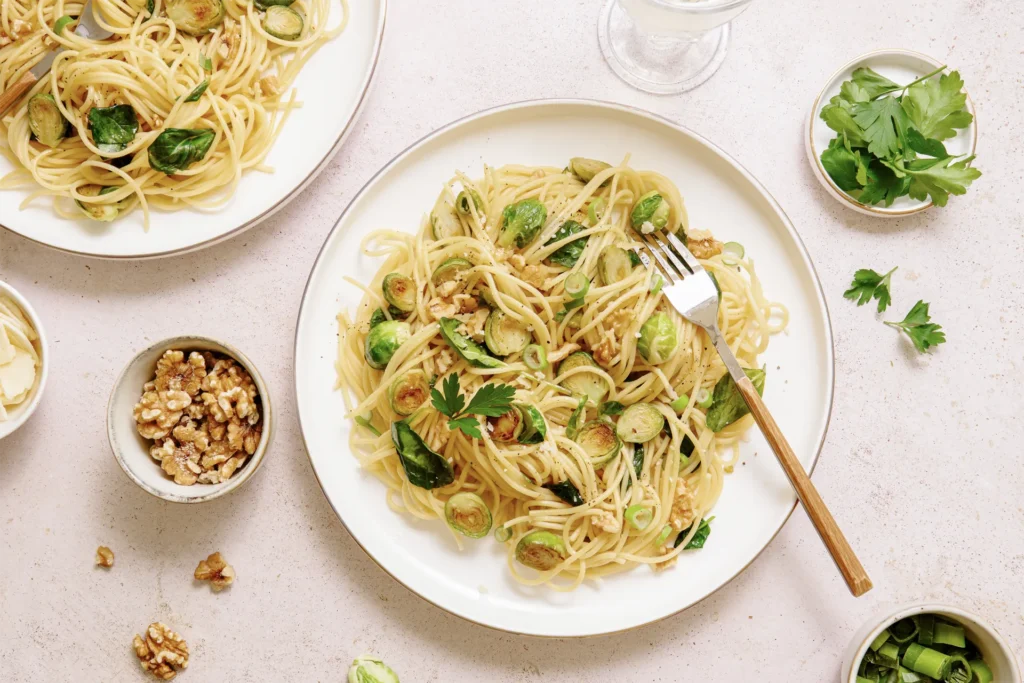 „Spaghetti mit Rosenkohl, Walnüssen und Spinat – winterliches Pastagericht mit knackigem Gemüse, nussiger Note und frischem Spinat auf rustikalem Teller.“