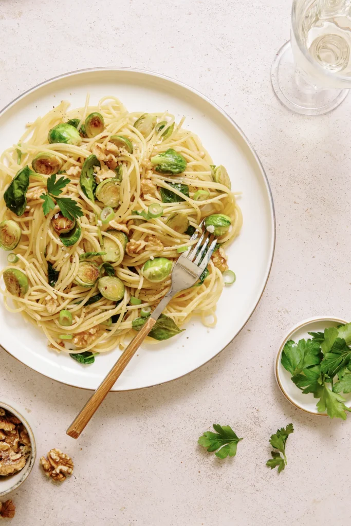 „Spaghetti mit Rosenkohl, Walnüssen und Spinat – winterliches Pastagericht mit knackigem Gemüse, nussiger Note und frischem Spinat auf rustikalem Teller.“