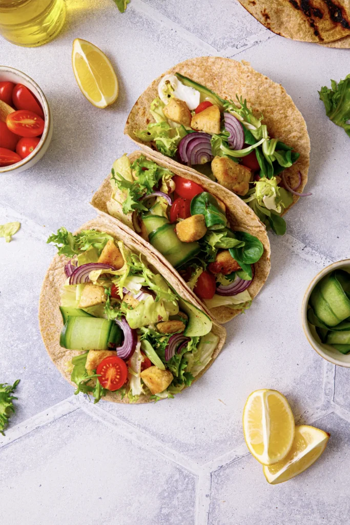 Hähnchen-Tacos mit frischem Salat, Tomaten, Gurken und roten Zwiebeln