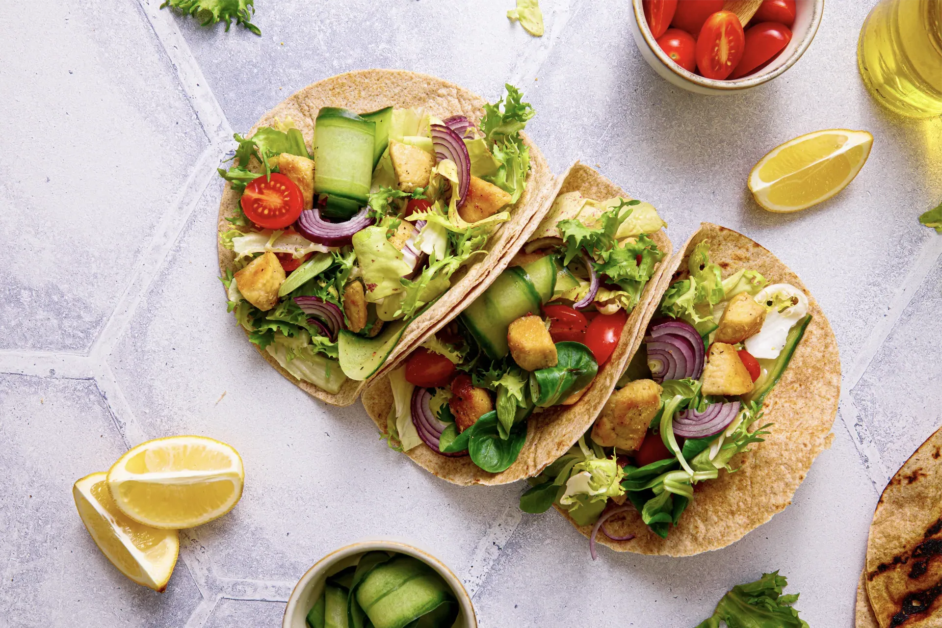 Hähnchen-Tacos mit frischem Salat, Tomaten, Gurken und roten Zwiebeln