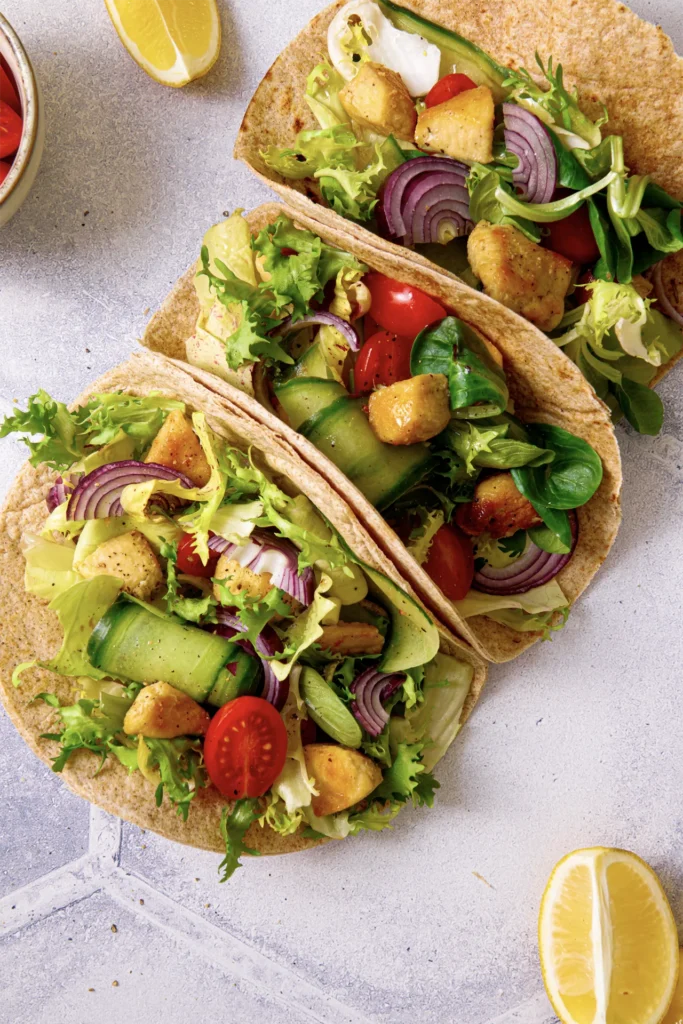 Hähnchen-Tacos mit frischem Salat, Tomaten, Gurken und roten Zwiebeln