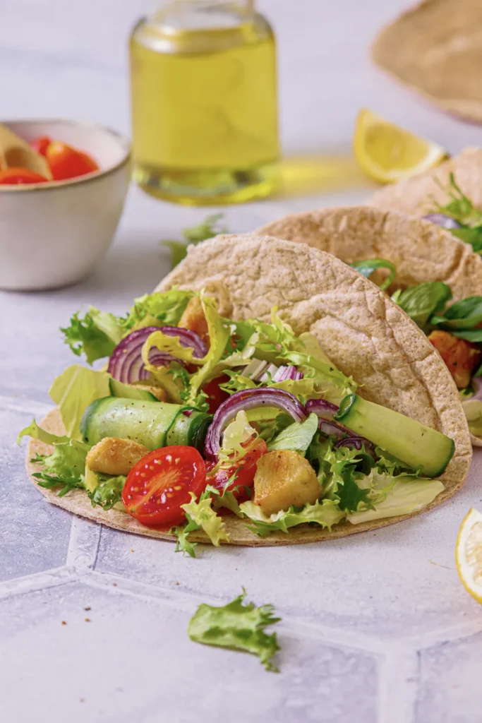 Hähnchen-Tacos mit frischem Salat, Tomaten, Gurken und roten Zwiebeln