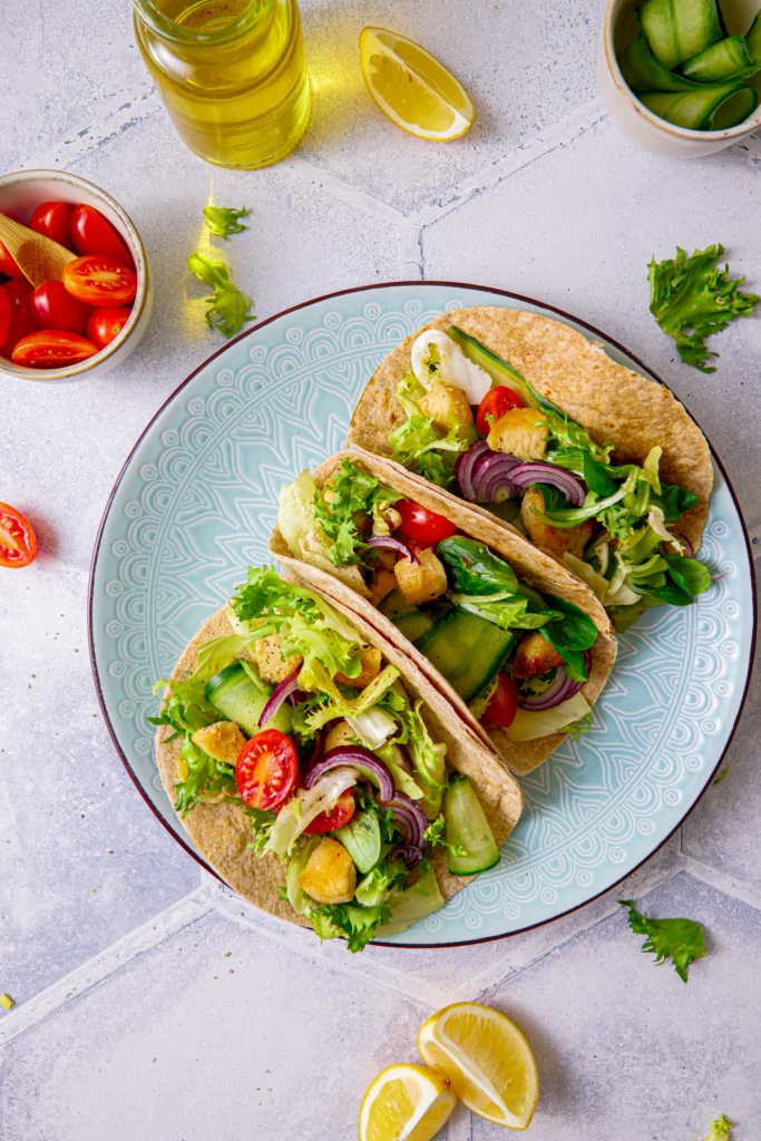 Hähnchen-Tacos mit frischem Salat, Tomaten, Gurken und roten Zwiebeln