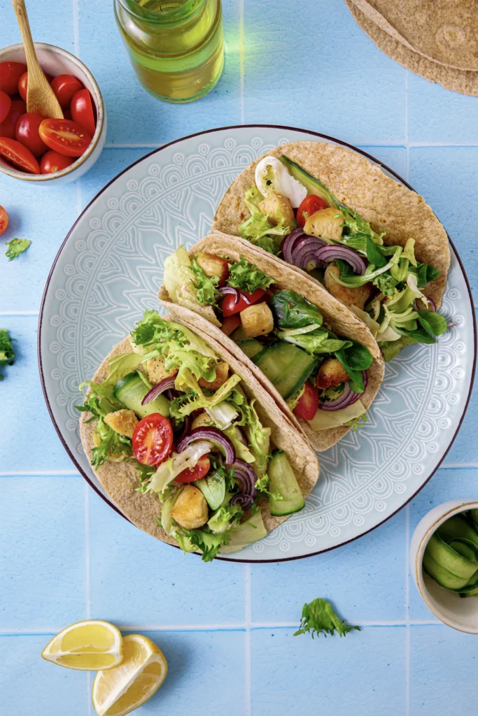 Hähnchen-Tacos mit frischem Salat, Tomaten, Gurken und roten Zwiebeln