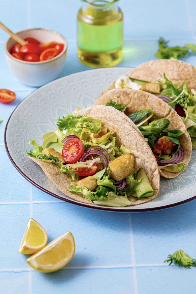 Hähnchen-Tacos mit frischem Salat, Tomaten, Gurken und roten Zwiebeln