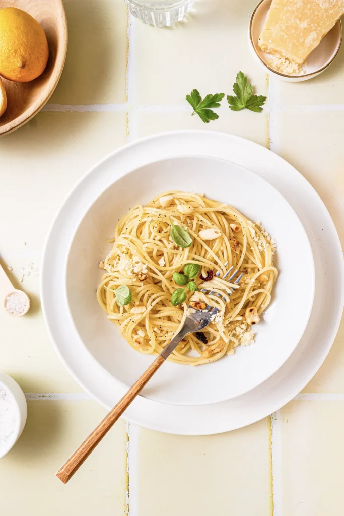 Ein Teller Zitronen-Pasta mit frischem Basilikum, Parmesan und einer Zitronenscheibe